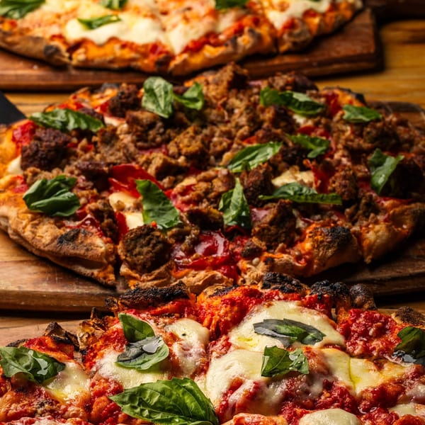 Three Mille Luci Pizzeria pizzas, one with sausage and basil, two with mozzarella, tomato sauce, and basil.