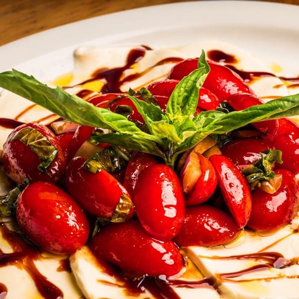 Close-up of a Mille Luci Pizzeria Caprese salad with fresh mozzarella, cherry tomatoes, and basil.