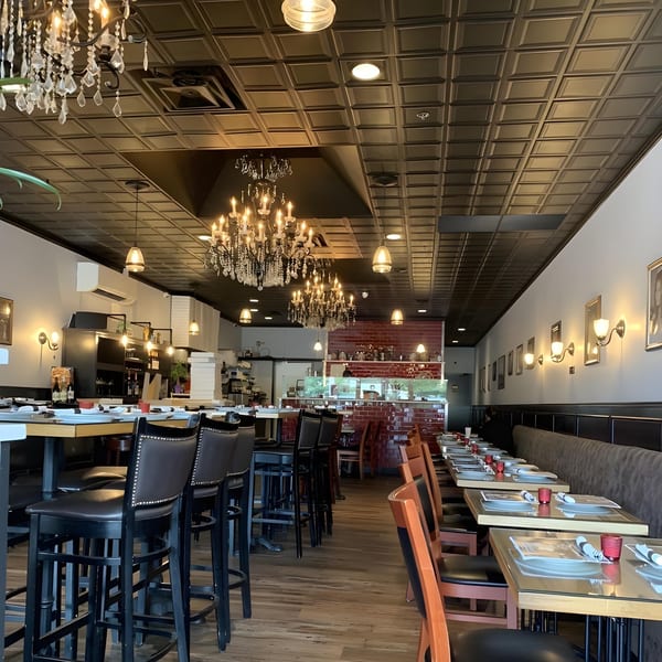 Mille Luci Pizzeria's dining room with high-top tables, chandeliers, and a red brick wall.