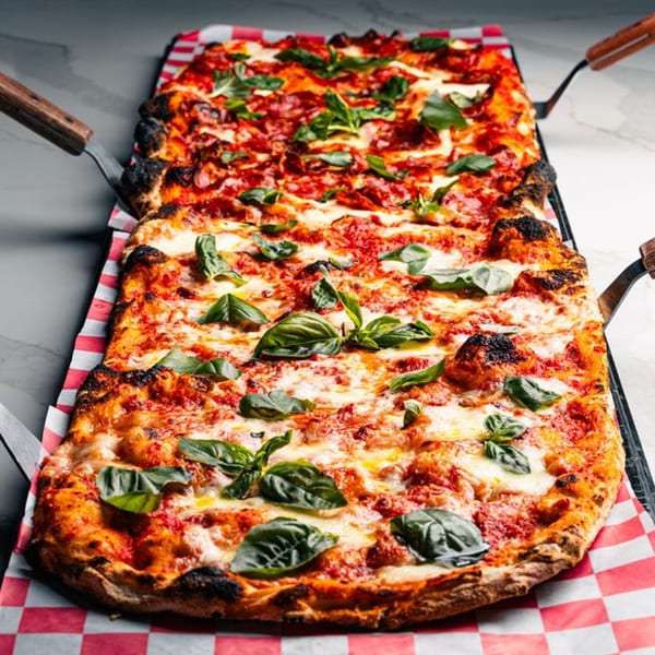 Two rectangular Mille Luci Pizzeria pizzas with melted cheese, red sauce, and fresh basil on checkered paper.